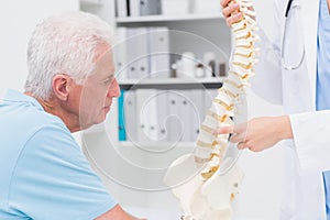 Doctor explaining anatomical spine to senior man