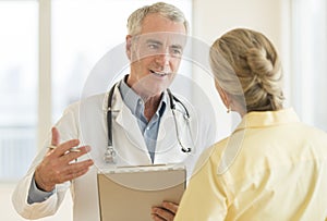 Doctor Explaining Report To Patient In Hospital