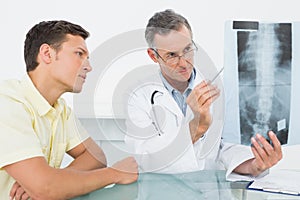 Doctor explaining spine xray to patient in office