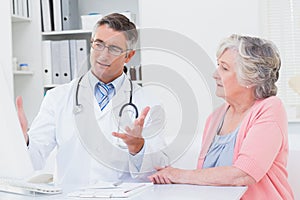 Doctor explaning reports to patient on computer