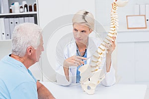 Doctor explaning spine model to senior patient