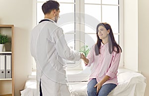 Doctor extends his hand to patient, signaling beginning of trusting relationship in medicine.