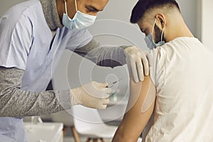 Doctor in face mask injecting patient with antiviral vaccine during immunization campaign