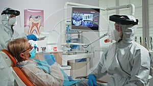 Doctor with face shield pointing on stomatological monitor