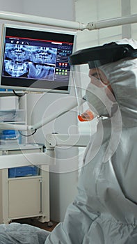 Doctor with face shield pointing on stomatological monitor