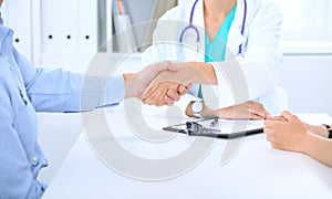 Doctor and family couple of patient are discussing something, just hands at the table. Medicine concept