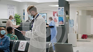 Doctor and female patient with face masks talking in waiting room