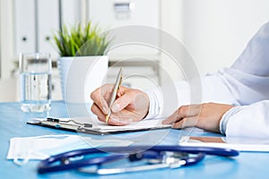 Doctor filling patient history list at clipboard