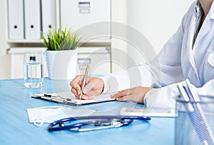 Doctor filling patient history list at clipboard