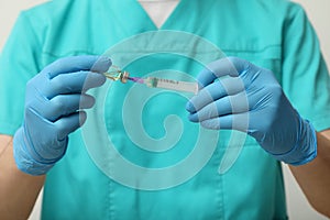 Doctor filling syringe with hepatitis vaccine from glass vial on grey background, closeup