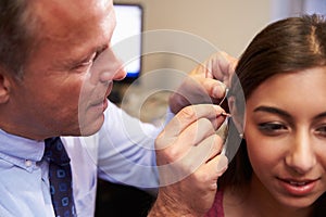 Doctor Fitting Female Patient With Hearing Aid