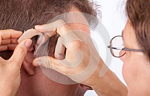 Doctor fitting senior man patient with hearing aid