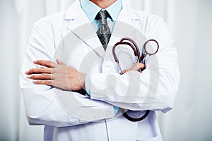 Doctor folding arms holding stethoscope