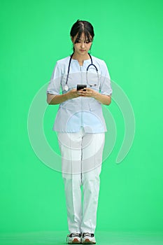 Doctor girl, on a green background, full-length, with a phone