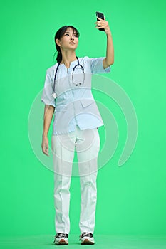 Doctor girl, on a green background, full-length, with a phone