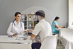 The doctor gives the patient a prescription while sitting at the table in the office of the clinic.Medical consultation.