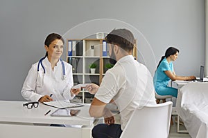 The doctor gives the patient a prescription while sitting at the table in the office of the clinic.Medical consultation.