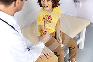 Doctor giving candy to kid in hospital stock photo