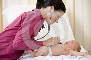 Doctor giving checkup with stethoscope to baby photo