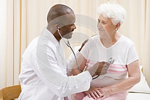 Doctor giving checkup with stethoscope to woman photo
