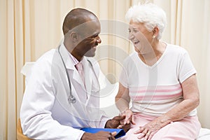 Doctor giving checkup to woman in exam room photo