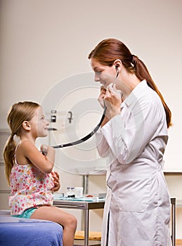 Doctor giving girl checkup in doctor office