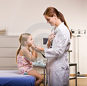 Doctor giving girl checkup in doctor office