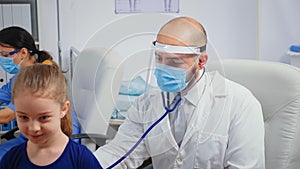 Doctor giving girl checkup in doctor office