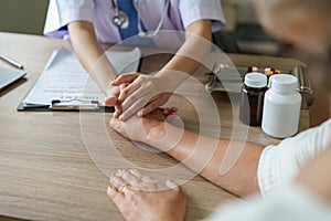 Doctor giving hope. Close up of doctor holding hand of elderly lady patient. Home healthcare nurse, physical therapy