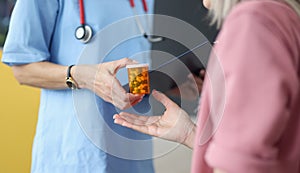 Doctor giving jar of pills to patient closeup