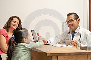 doctor giving a lollipop to a little girl as a reward. Pediatrician giving a candy to a child, building kid patient confidence