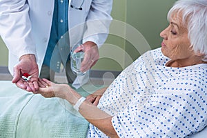 Doctor giving medicine pill to senior patient