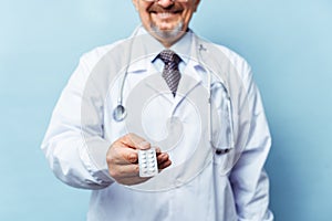 Doctor giving medicine pills. on blue background. The concept of medicine, pharmacology, healthcare.