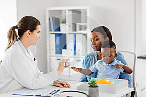 Doctor giving medicine to woman with son at clinic