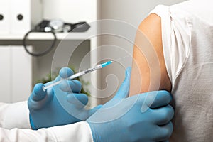 Doctor giving patient vaccine, flu shot. Doctor making a vaccination in the shoulder of patient