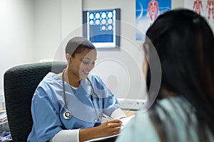 Doctor giving prescription to pregnant woman at desk