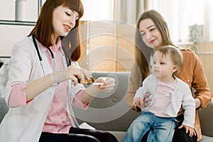 Doctor giving a spoon of syrup to little kid girl