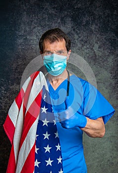 Doctor giving a thumbs up sign, wearing face mask and holding the American flag