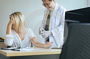 Doctor giving vaccine to woman patient with injection or syringe in hospital room