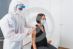 Doctor giving a vaccine to a pregnant woman against Covid 19 or flu or whooping cough.