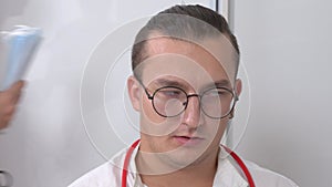 Doctor with glasses rolls eyes woman with folders walks
