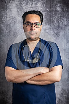 doctor in glasses with a stethoscope near a gray wall. Space for text