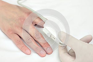 Doctor in a glove puts the sensor on patient's finger. Symbol of