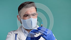 Doctor in gloves amd mask flicks syringe prior to drug injection, to collect and release the air out of syringe. Bearded