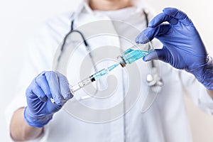 Doctor in gloves filling up syringe from bottle with vaccine, medicine