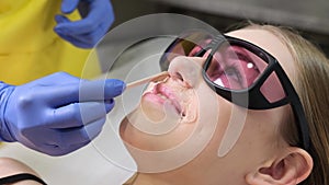 A doctor in gloves removes facial hair from a woman using a modern laser. Epilation for smooth skin