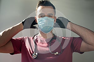 The doctor with gloves and a stethoscope puts on a mask