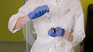 Doctor in gloves taking medicine from vial with syringe