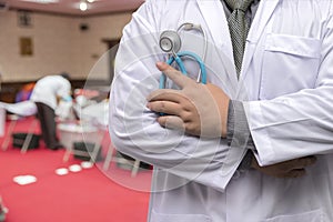 Doctor in gown uniform with stethoscope standing and fold his arms over the chest in blood donor room