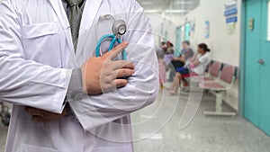 Doctor in gown uniform with stethoscope standing and fold his arms over the chest on OPD background